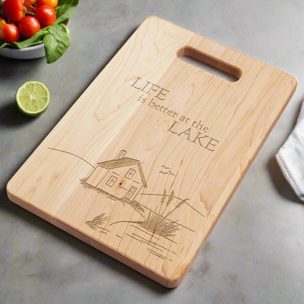 Maple cutting board with engraved lake house on a marble countertop with a salad bowl and a lime